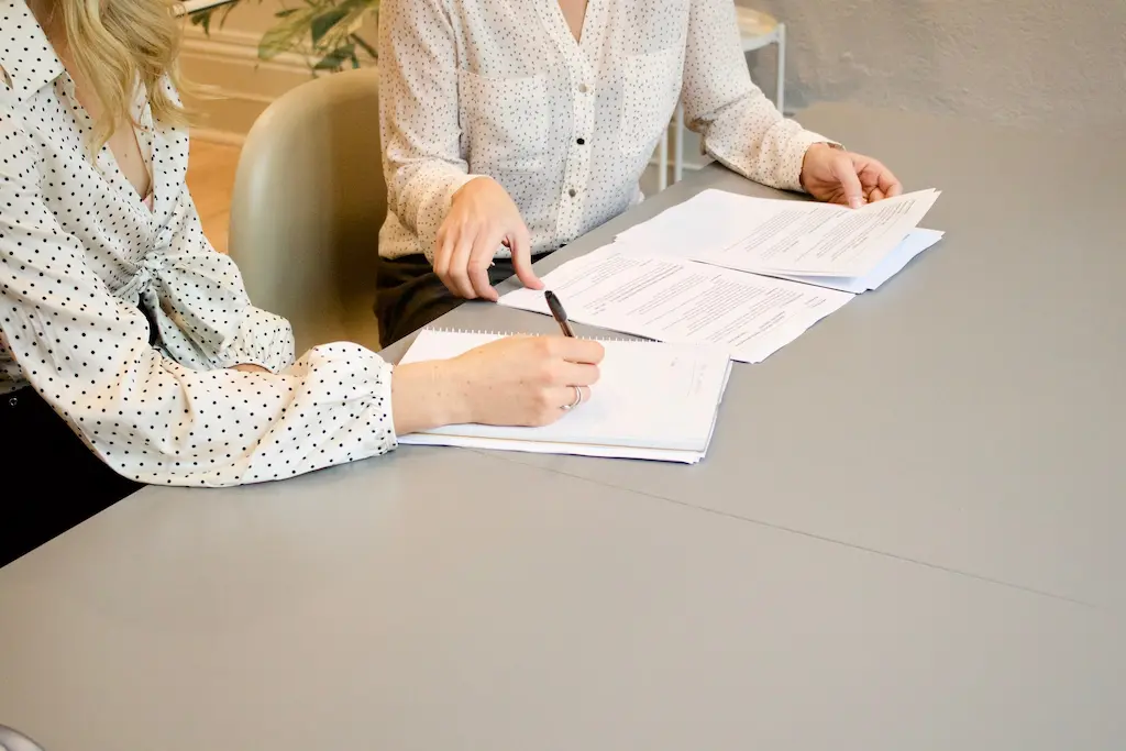 Two women running through rental terms before signing a lease
