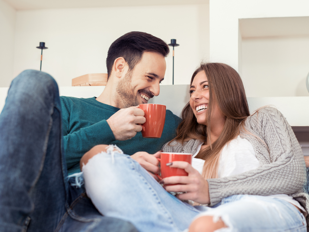 A young couple relaxing on the couch at home enjoying a coffee