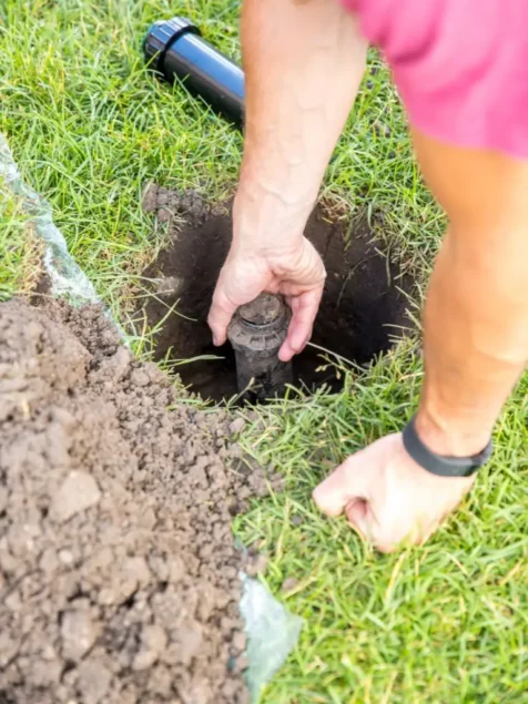 An irrigation technician replacing a broken sprinkler